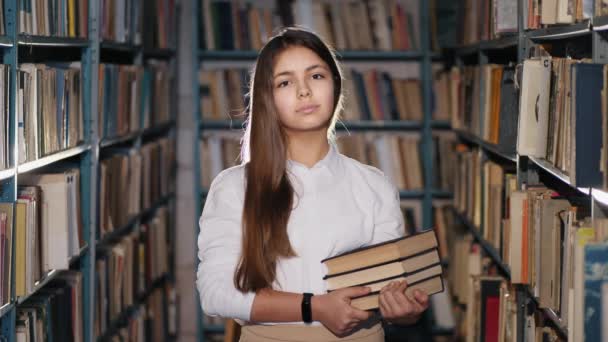 Portrait of a teen girl with books in the library — Stock Video