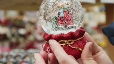 Karlı Noel küresi oyuncağının yakın çekimi kadınların elinde