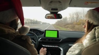 Noel Baba şapkalı genç çift arabalarında yeşil ekran kullanıyor.