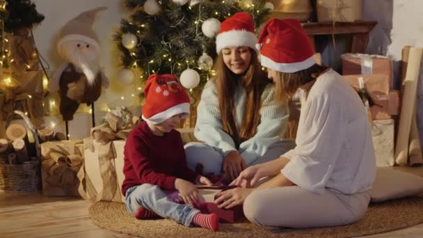 Een gezin van drie opent een kerstcadeau — Stockvideo