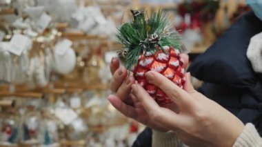 Panayırdaki bir kadının elinde Noel oyuncağı kozalağı