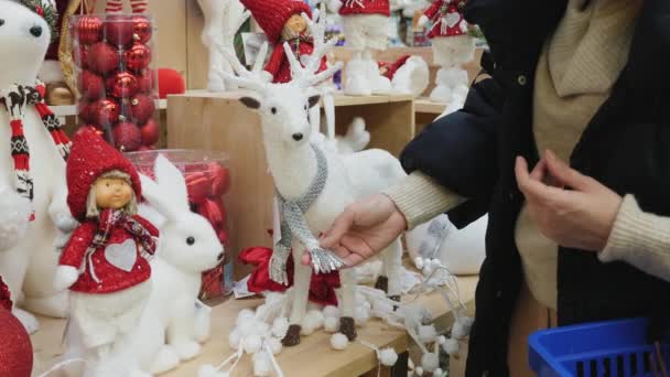 Mulher compras no mercado de Natal examinando brinquedo veado branco — Vídeo de Stock