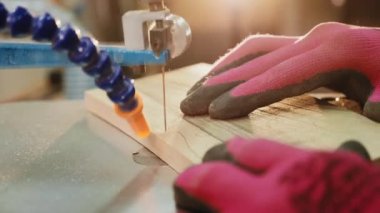 Marangoz elektrikli testere makinesiyle ahşap bir kalas kesiyor.