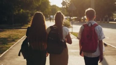 Okul çağındaki üç arkadaşın arka planı caddede yürüyor.