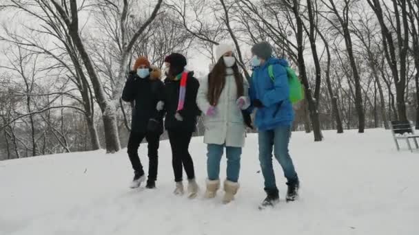Schulkinder mit Masken werfen im Winter Schneebälle in den Park — Stockvideo