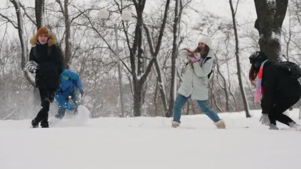 Adolescentes se divertem jogando neve uns nos outros no parque da cidade — Vídeo de Stock