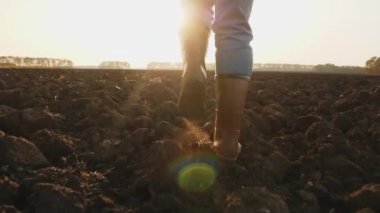 Lastik çizmeli çiftçi tarlada yürüyor.