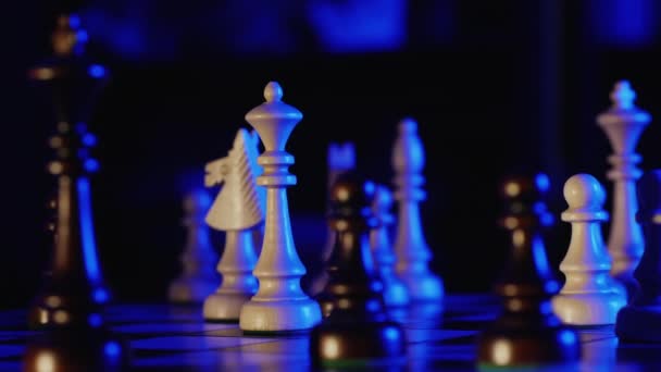 Wooden chess pieces on a chessboard in a dark room with blue backlight — Stock Video