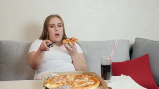 Mujer con sobrepeso comiendo pizza y viendo televisión — Vídeos de Stock