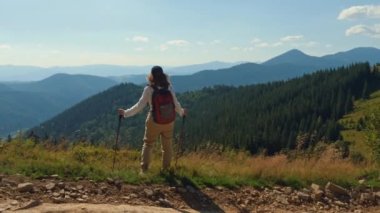 Dağın tepesinde duran sırıklı kadın.