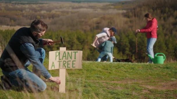 Un hombre coloca un signo con las palabras Planta un árbol — Vídeos de Stock