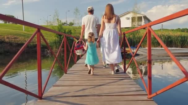 Keluarga berjalan di jembatan di atas sungai untuk piknik — Stok Video