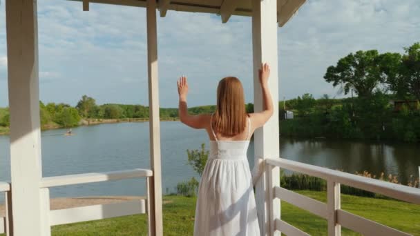 Jovem mulher ondas para seu marido que está pescando no lago — Vídeo de Stock