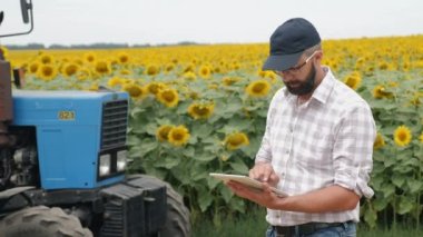 Farmer uses digital tablet in the field near the tractor