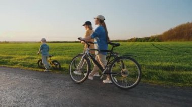 Woman with children walking along the road holding bicycles in their hands