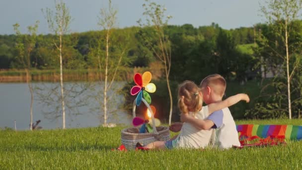 Petit garçon et fille s'embrassent tout en étant assis sur l'herbe — Video