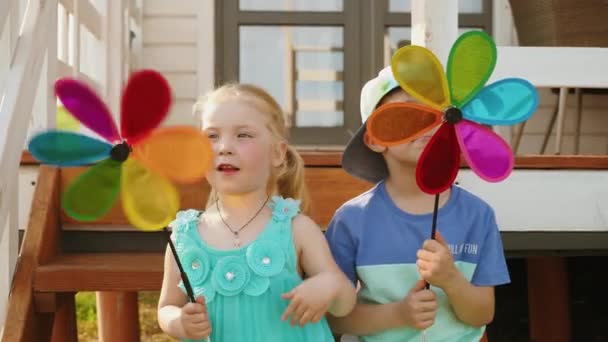 Petits enfants assis sur les marches jouant avec un jouet de moulin à vent — Video