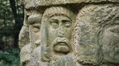 Ormanda insan yüzlerinin oyulmuş heykeli.