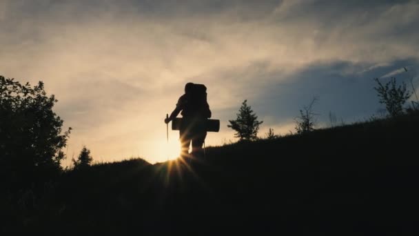 Rear view silhouette of walking man with backpack on the mountain — Stock video