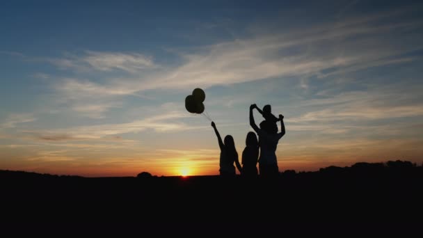 Silhuetter av en familj med barn tittar på en vacker solnedgång tillsammans — Stockvideo