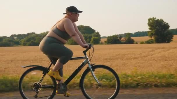 Młoda plus size kobieta jeździ na rowerze sportowym po drodze — Wideo stockowe