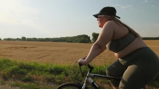 Młoda gruba kobieta w odzieży sportowej jeździ na rowerze — Wideo stockowe