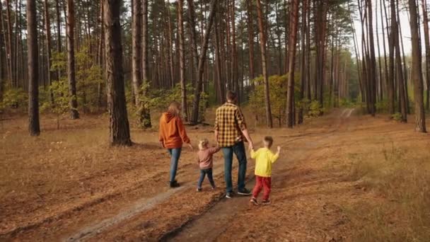 En familj på fyra med hund går i tallskog. — Stockvideo