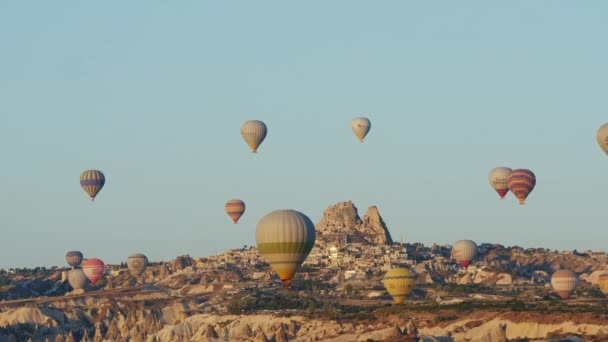 Balões multicoloridos voam sobre o vale e a cidade no início da manhã — Vídeo de Stock