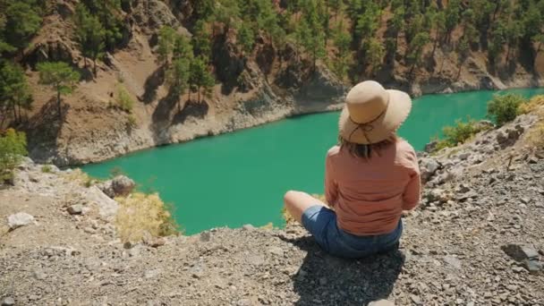 Žena sedící na okraji hory s výhledem na řeku Zamanti — Stock video