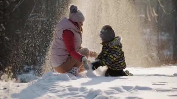 Lykkelig mor med lille søn leger med sne, kaster den op – Stock-video