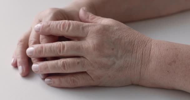白いテーブルの上に高齢女性の手の閉鎖 ビデオは 一方が他方をカバーし わずかな指の動きを作る — ストック動画