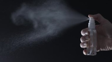 Sprey bir sıvı akışı püskürtür. Siyah arka planda antiseptik damlalar. Yavaş çekim.