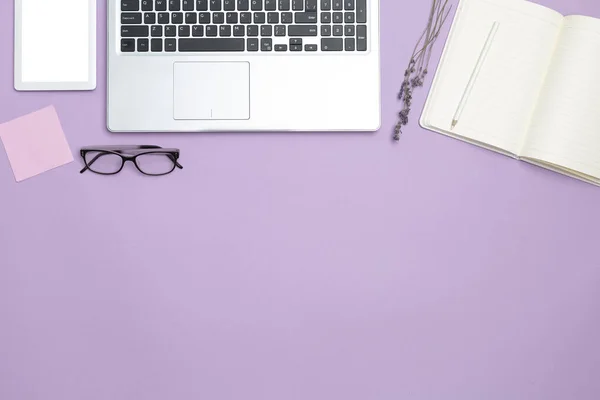 Stylish work feminine business desk with laptop and modern office attributes. Top view. Copy space. Flat space. Purple background.