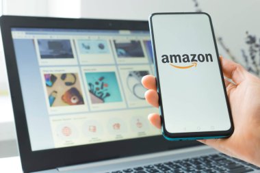 Kyiv, Ukrayna - Şubat 02, 2021: Akıllı telefon ve dizüstü bilgisayar kullanarak Amazon çevrimiçi mağazasından mal satın almak.