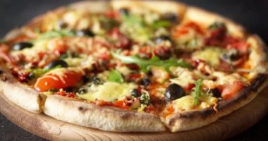 Peynirli, domatesli, zeytinli ve roka kaplı taze pizza..