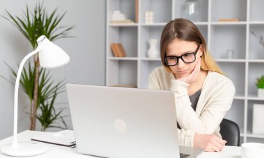 Kız öğrenci internetteki bir dersi özenle bir dizüstü bilgisayar kullanarak dinliyor. Genç bir kadın konsantrasyonuyla bilgisayar ekranına bakıyor. Uzaktan eğitim.