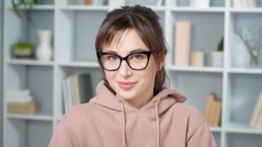 Gözlüklü kadın kameraya bakıyor.