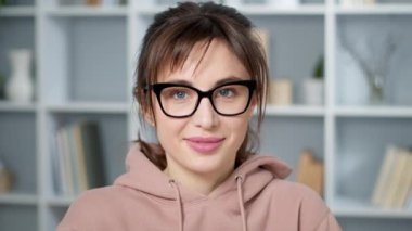 Gözlüklü kadın kameraya bakıyor ve gülümsüyor.