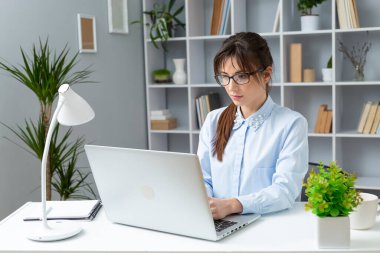 Gözlüklü kadın dizüstü bilgisayarda çalışıyor. 