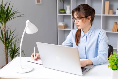 Gözlüklü kadın dizüstü bilgisayarda çalışıyor. 