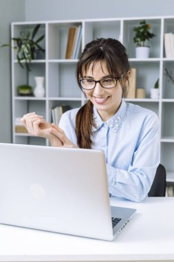 Gözlüklü kadın dizüstü bilgisayarda çalışıyor. 