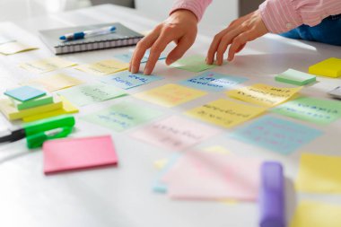 İş kadını masaüstündeki notları kullanarak bir proje üzerinde çalışıyor. Şirketin gelişimi için yeni fikirler bulmak için beyin fırtınası..