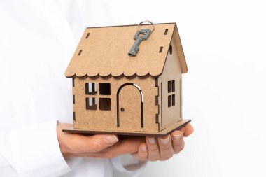 Bir model ev ve bir emlakçının elinde bir anahtar..