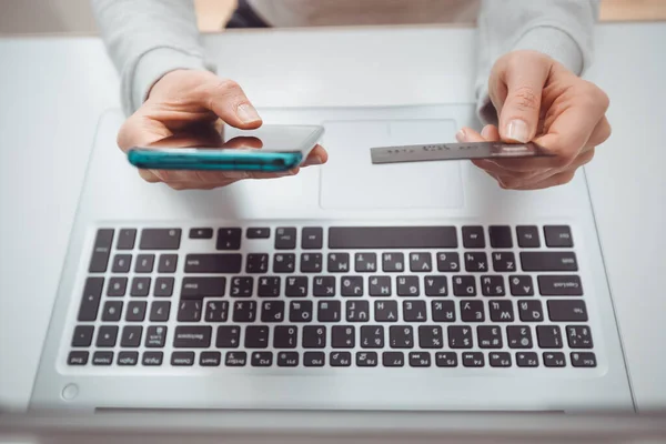 E-commerce via laptop. Using a phone and a credit card to buy and pay in an online store. Shopping remotely on a smartphone.