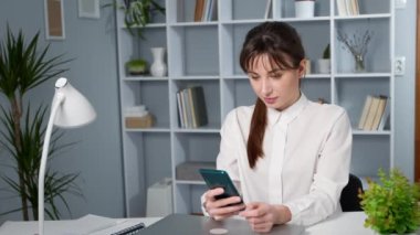 Mutlu genç bayan telefonda mutlu haberler okuyor ve şaşırıyor. Akıllı telefona bakan başarılı bir kızın portresi. Mutluluk ve zafer duygusu..