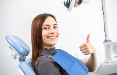 Mutlu genç kadın hasta jinekoloğun ya da dişçinin tıbbi koltuğunda oturuyor..