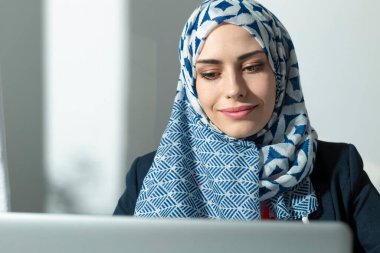 Bilgisayar ekranına bakan tesettürlü Arap genç kadının portresi