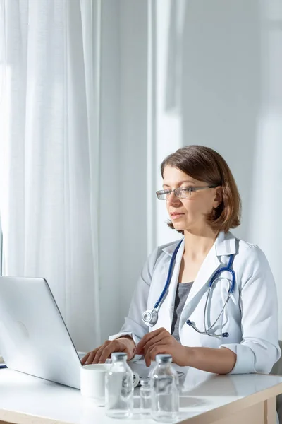 Médico Femenino Sentado Escritorio Con Frascos Uso Computadora Portátil Luz —  Fotos de Stock