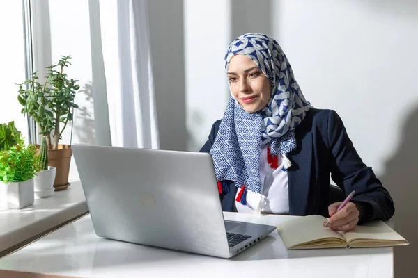 Perempuan Muda Mengenakan Jilbab Mencari Komputer Dan Menulis Dengan Pena — Stok Foto