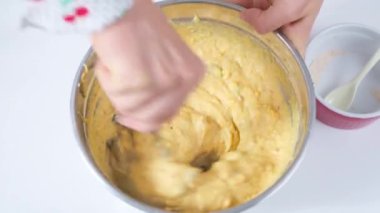 Kadın pasta şefi hamur ve kurutulmuş meyveyi kek pişirmek için karıştırıyor.. 